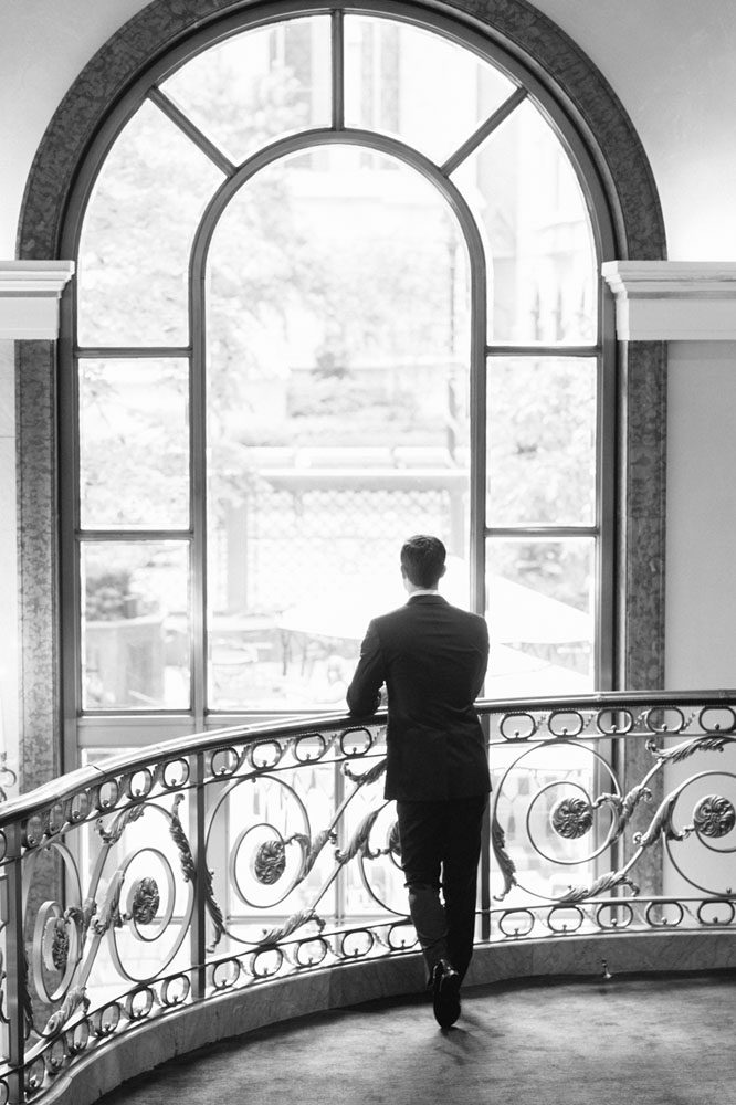 The groom stands on the balcony in a reflective mood