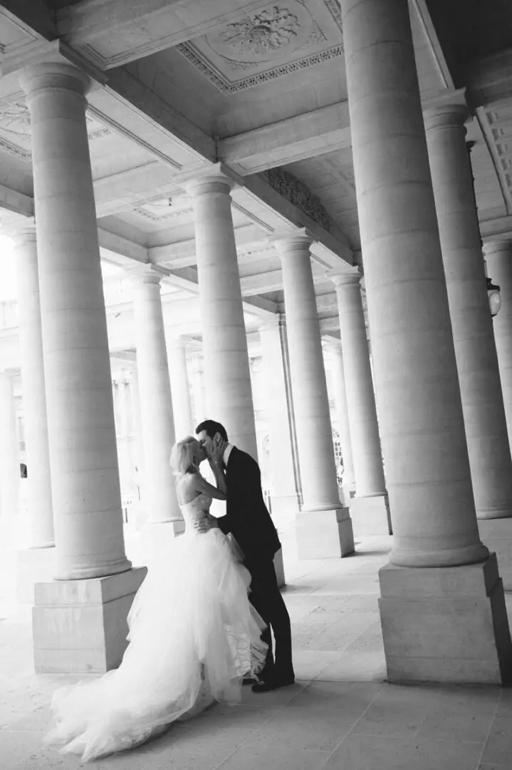 The bride and the groom kissing under a building