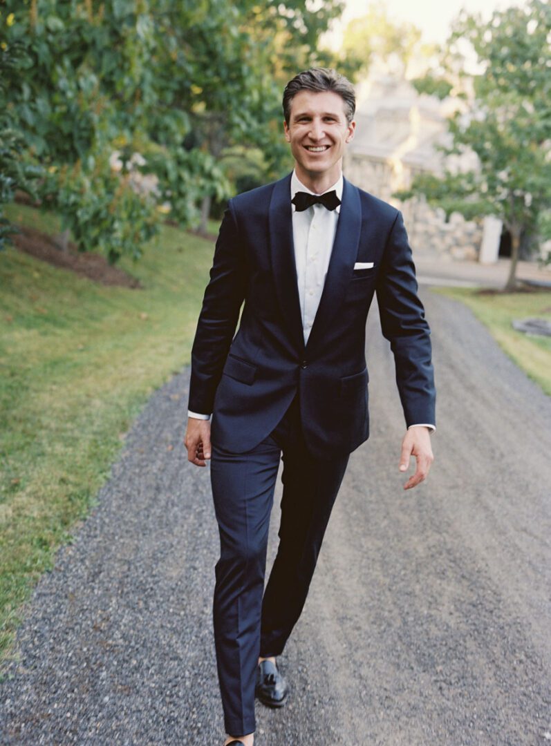 The groom looks elegant as he walks down the road