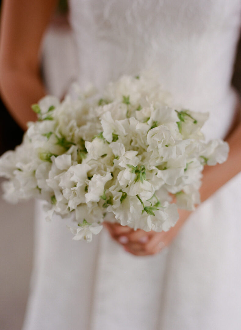 The bride holds the white bouquet of flowers