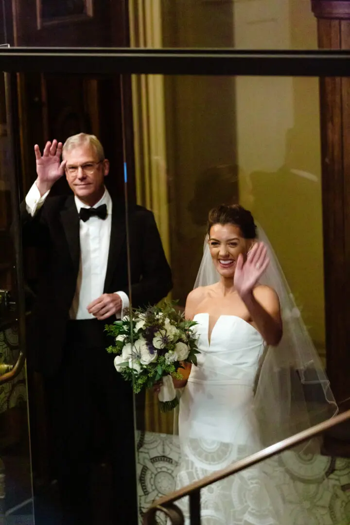 The bride and her father wave to the wedding attendees