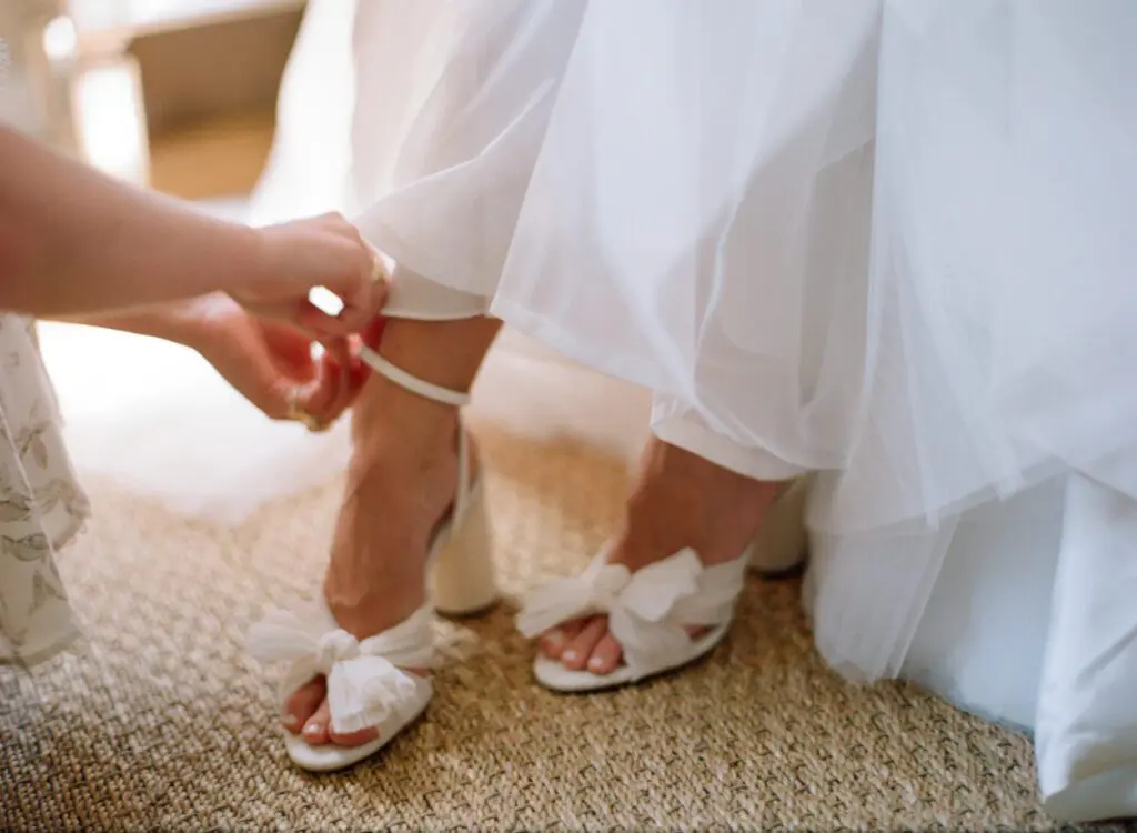 The bride is assisted while wearing her wedding heels