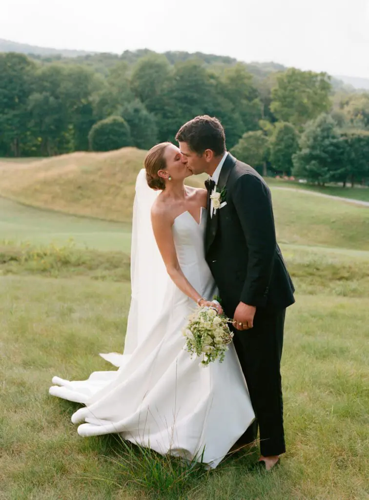 The bride and the groom kiss amidst greenery