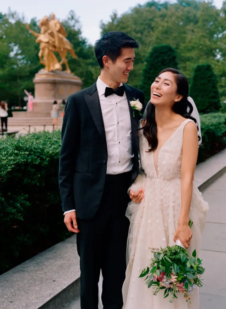 Newlywed couple laughing together with bouquet in hand