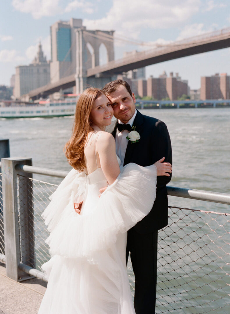 A newlywed couple standing in front of a river