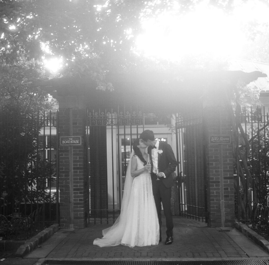 Newlywed couple kissing in front of a gate