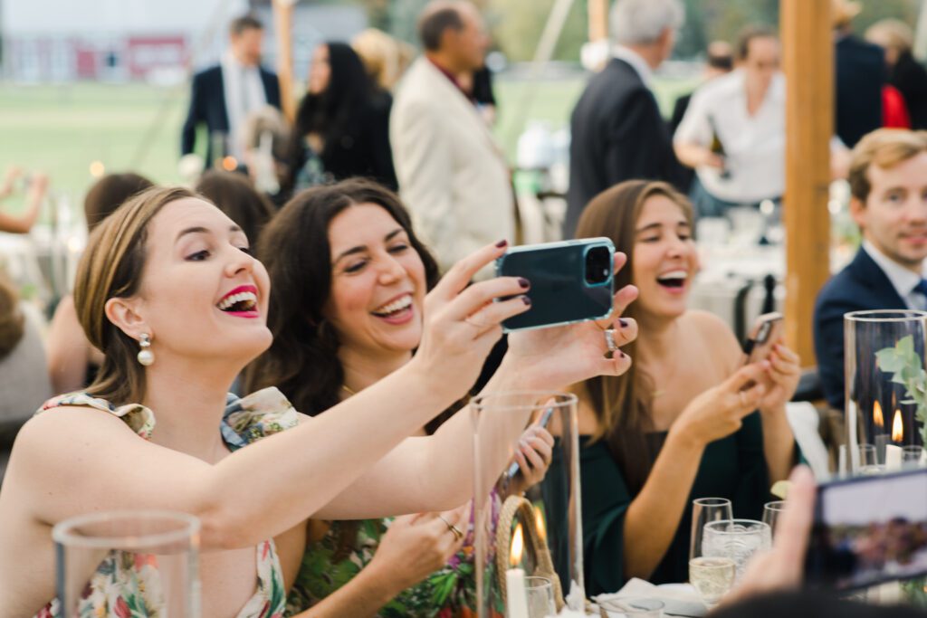 Group of women at the wedding clicking pics on iPhone
