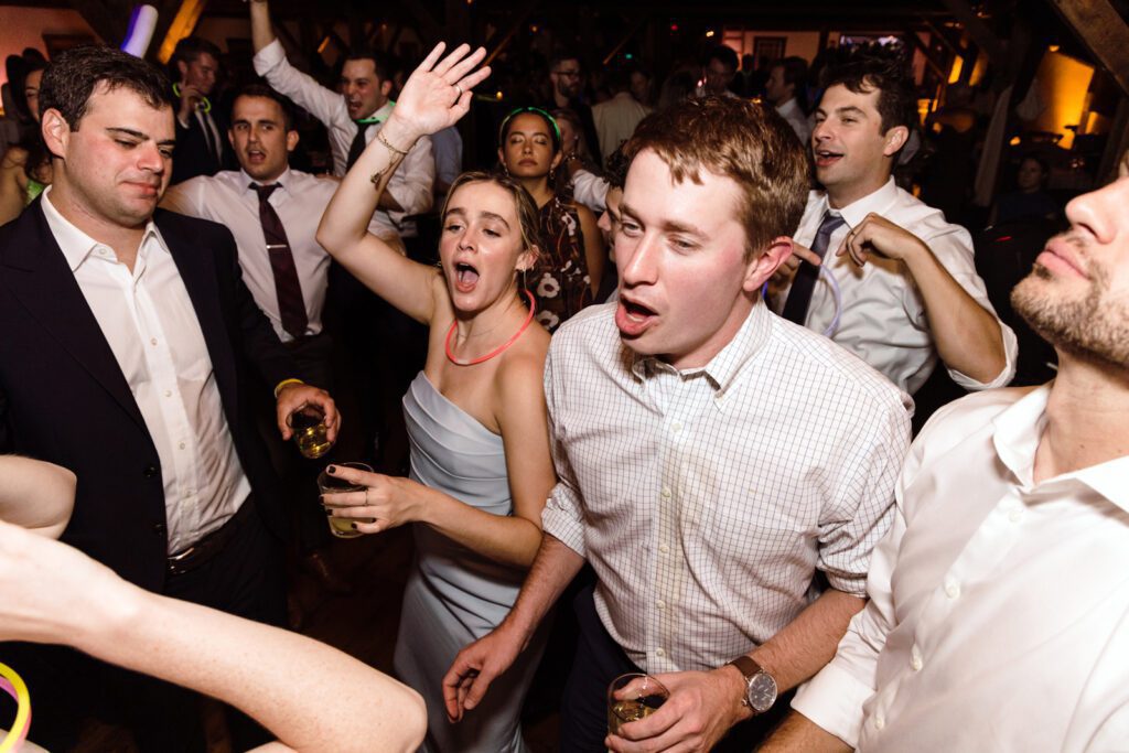 Bride and groom dancing at a party holding drinks