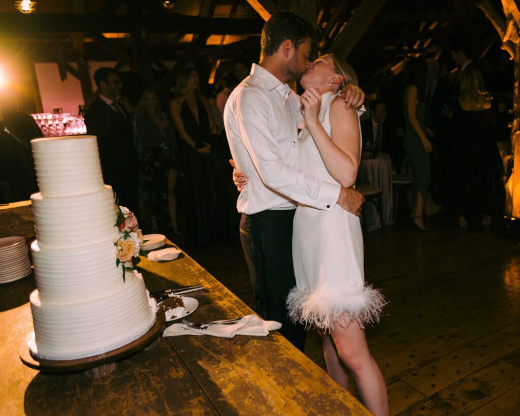 Bride and groom kissing and a table with wedding cake