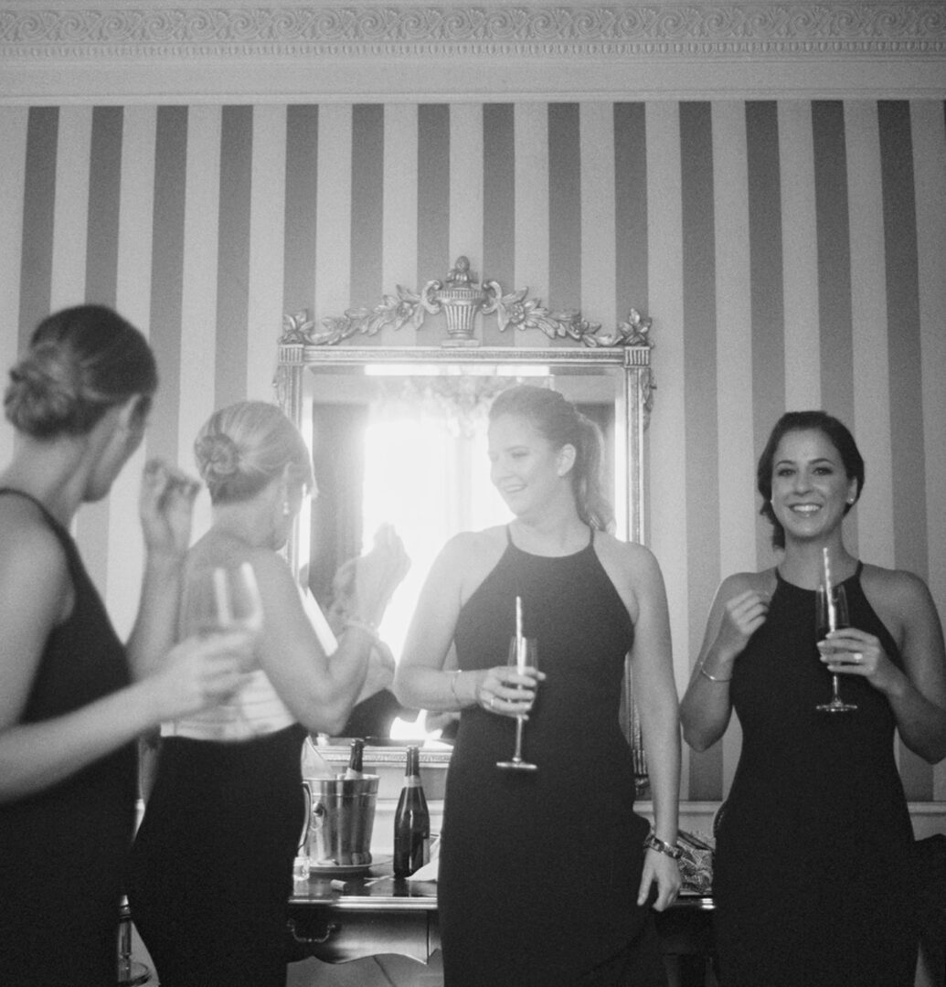 Four women in black dress holding wine glasses