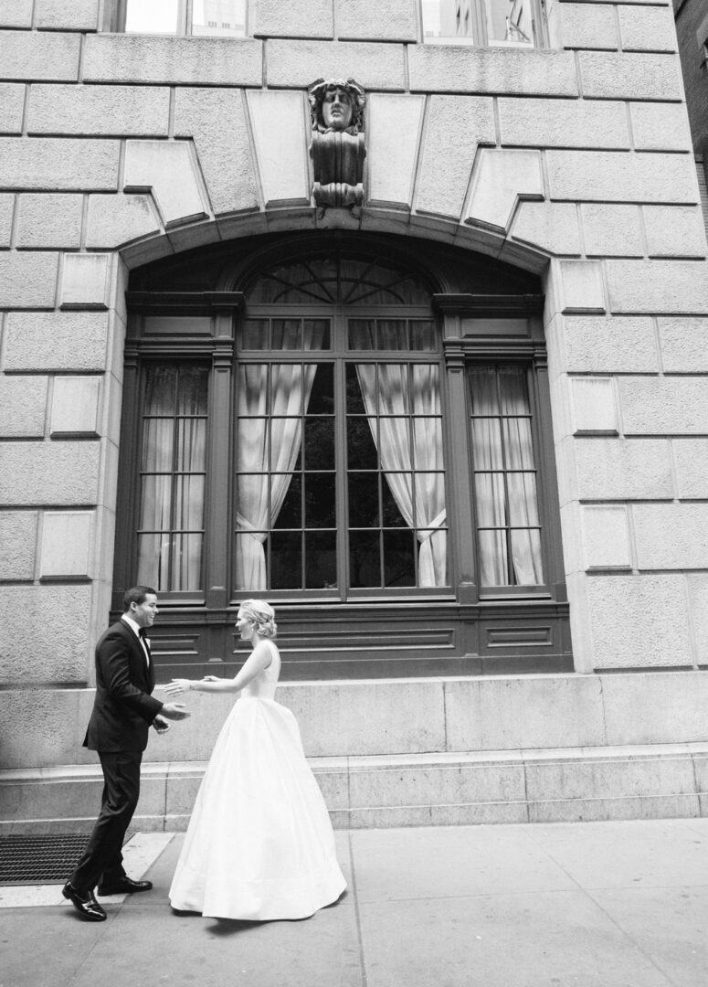 Bride and groom holding hands in front of a building