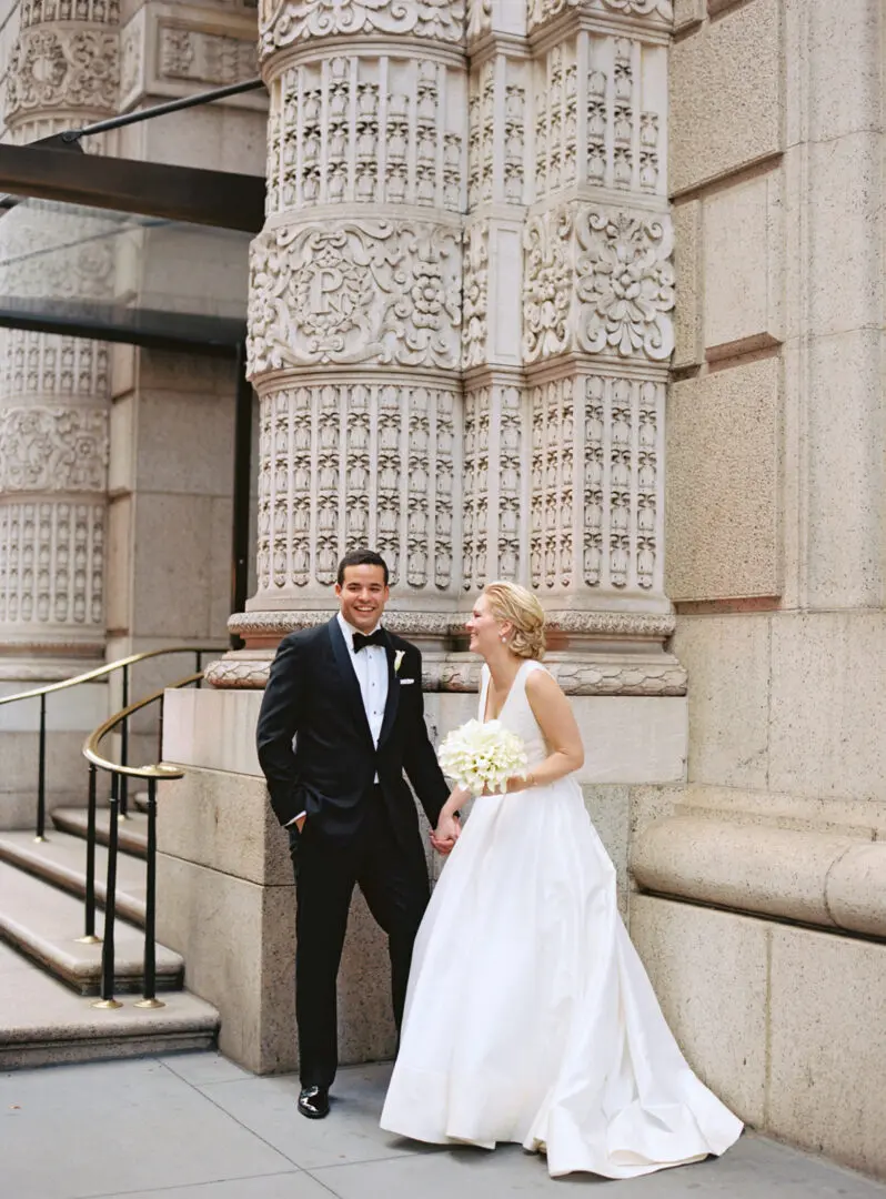 Bride and groom smiling in front of the building