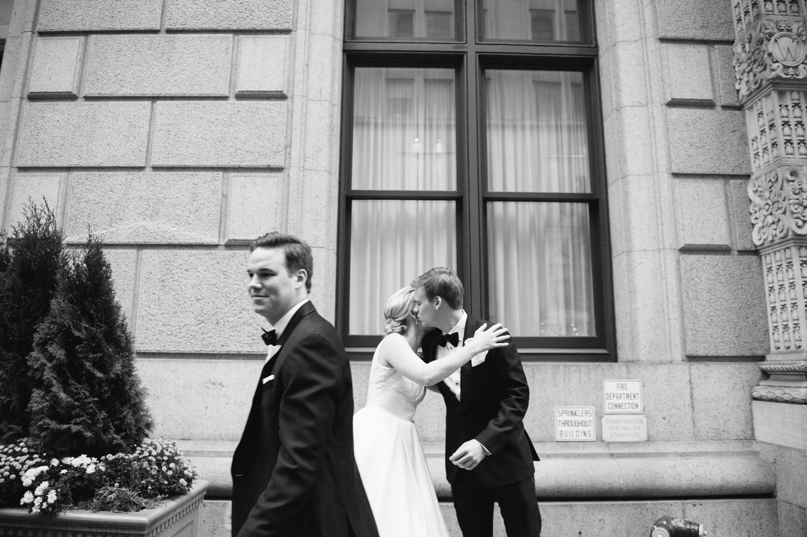 Bride and groom kissing and a man passing by