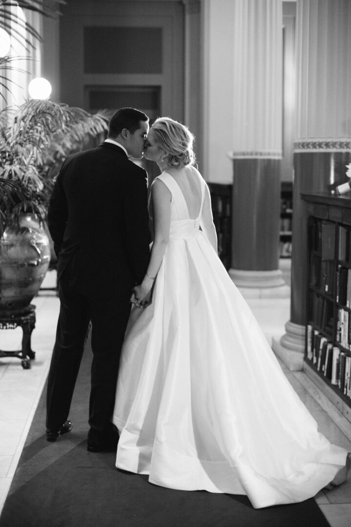 Bride in white gown and groom in black suit kissing