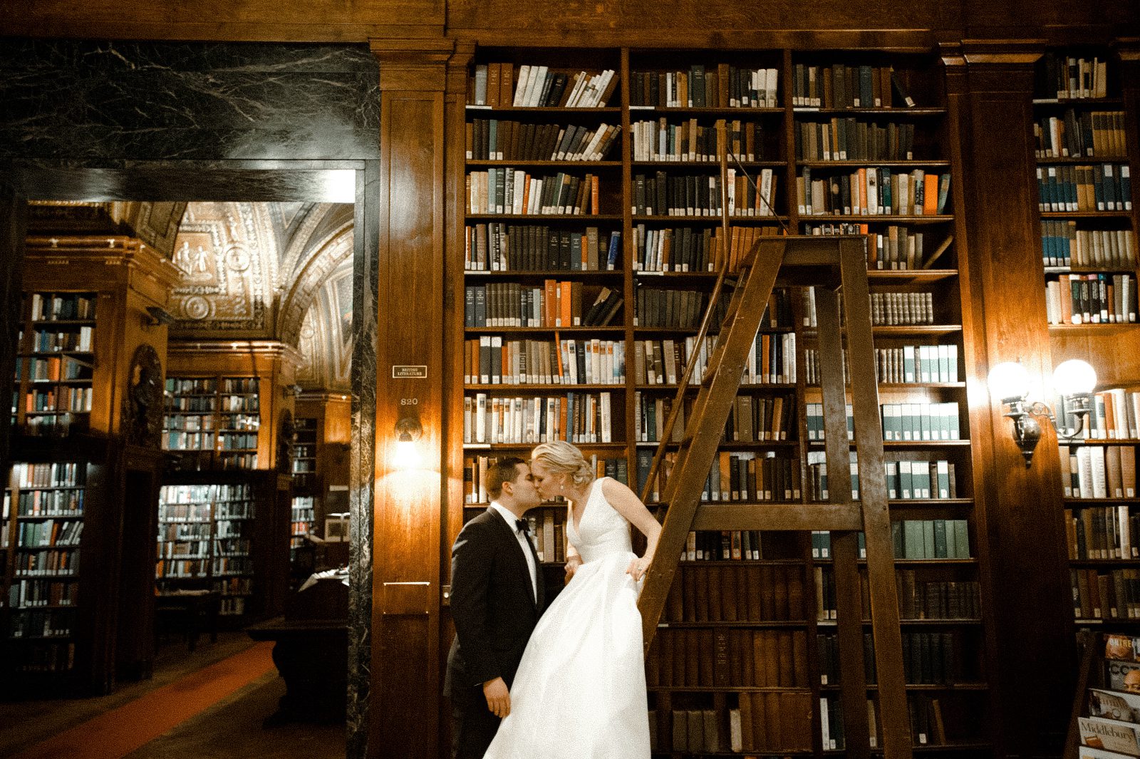 Bride and groom kissing inside a library