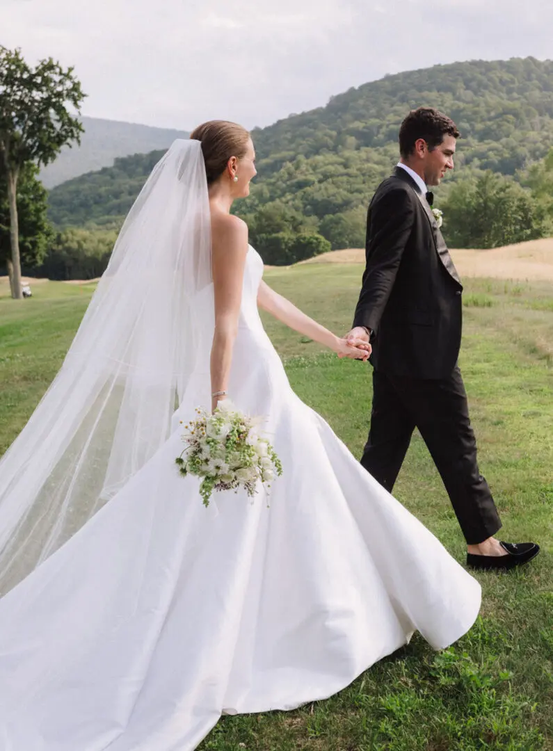 Newlywed couple walking in field holding each other hand