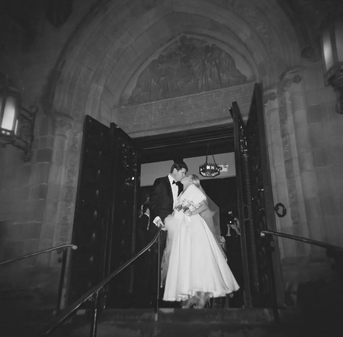 Black and white image of a couple kissing on the stairs