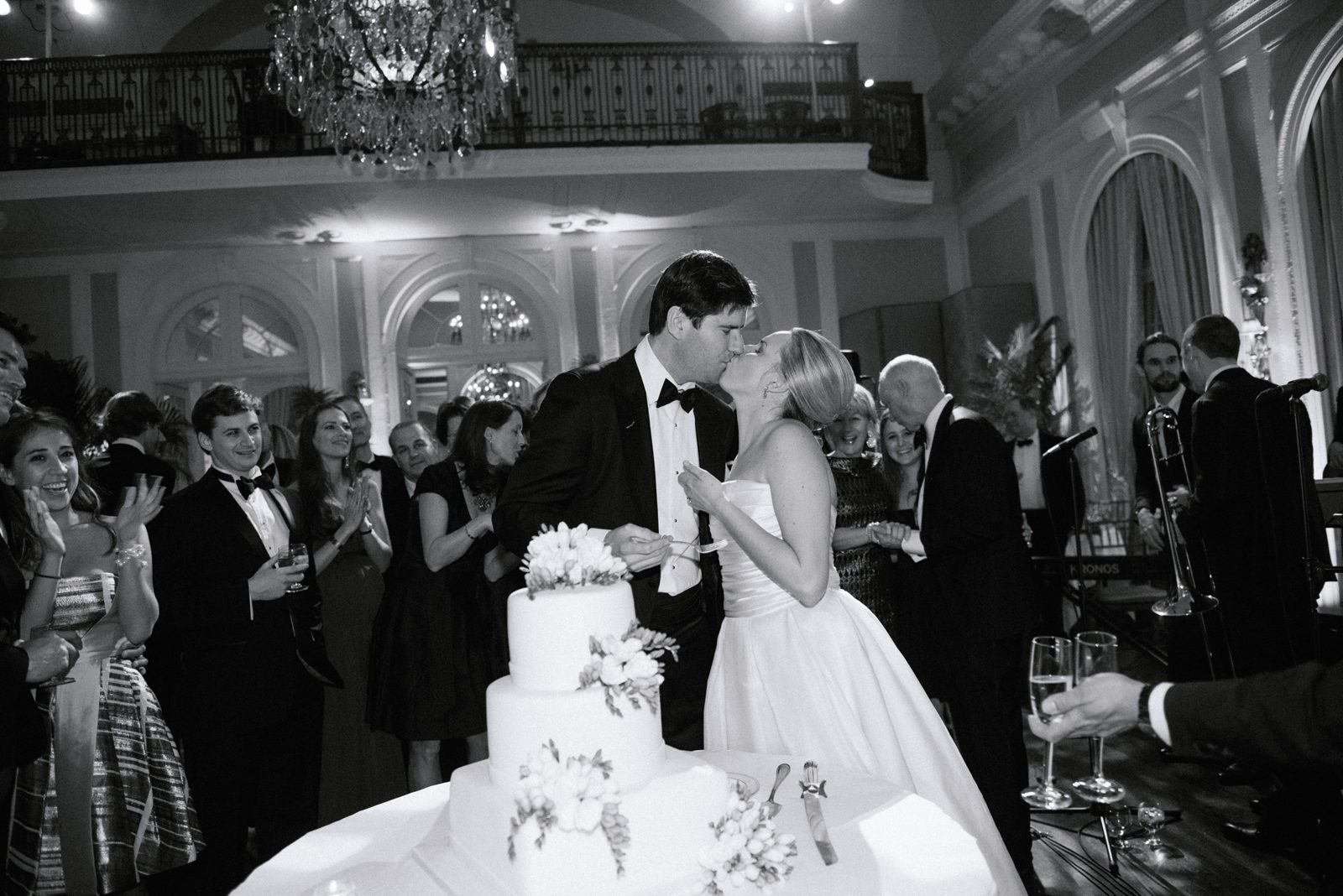 Black and white image of couple kissing while cutting cake