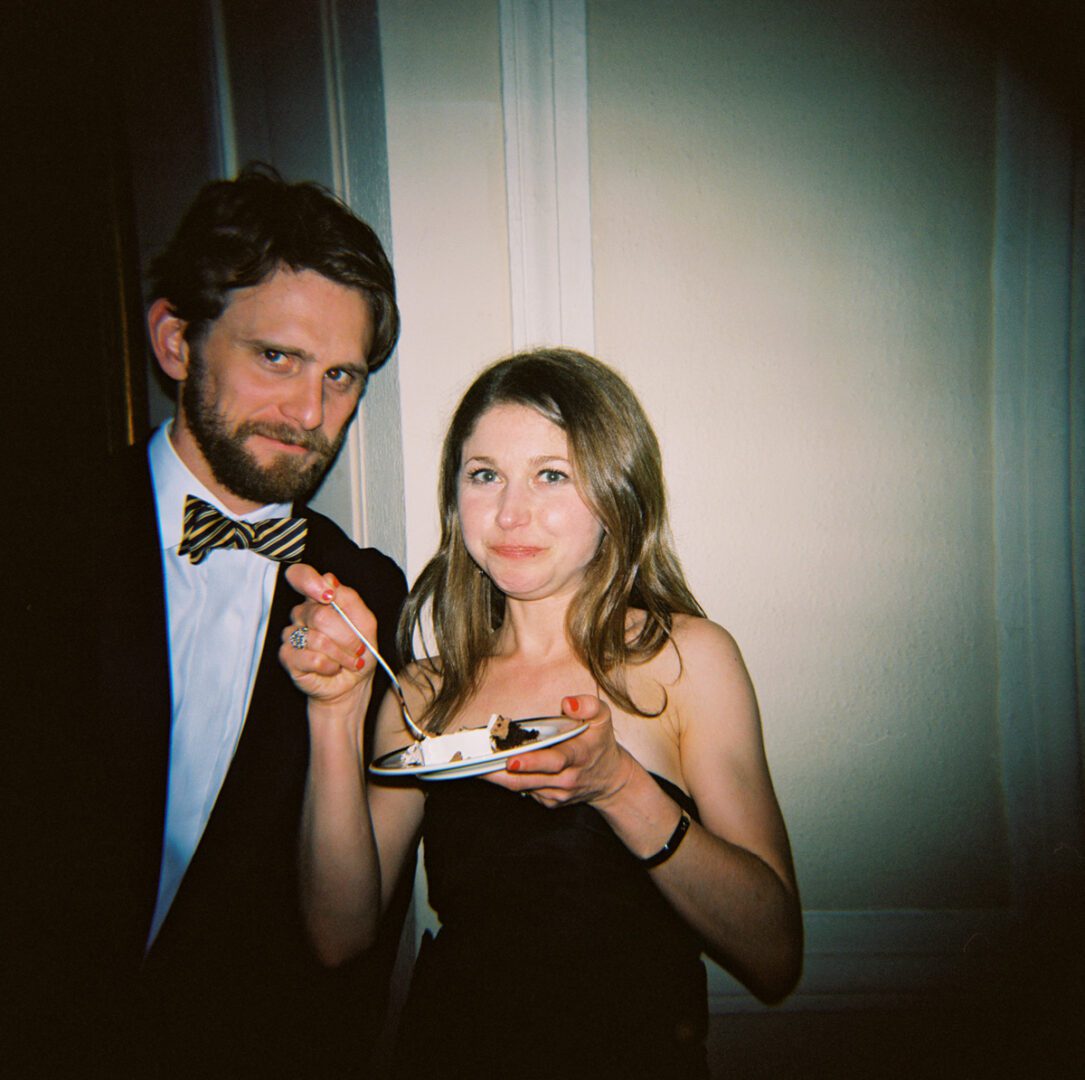A girl eating cake with a man smiling at the camera