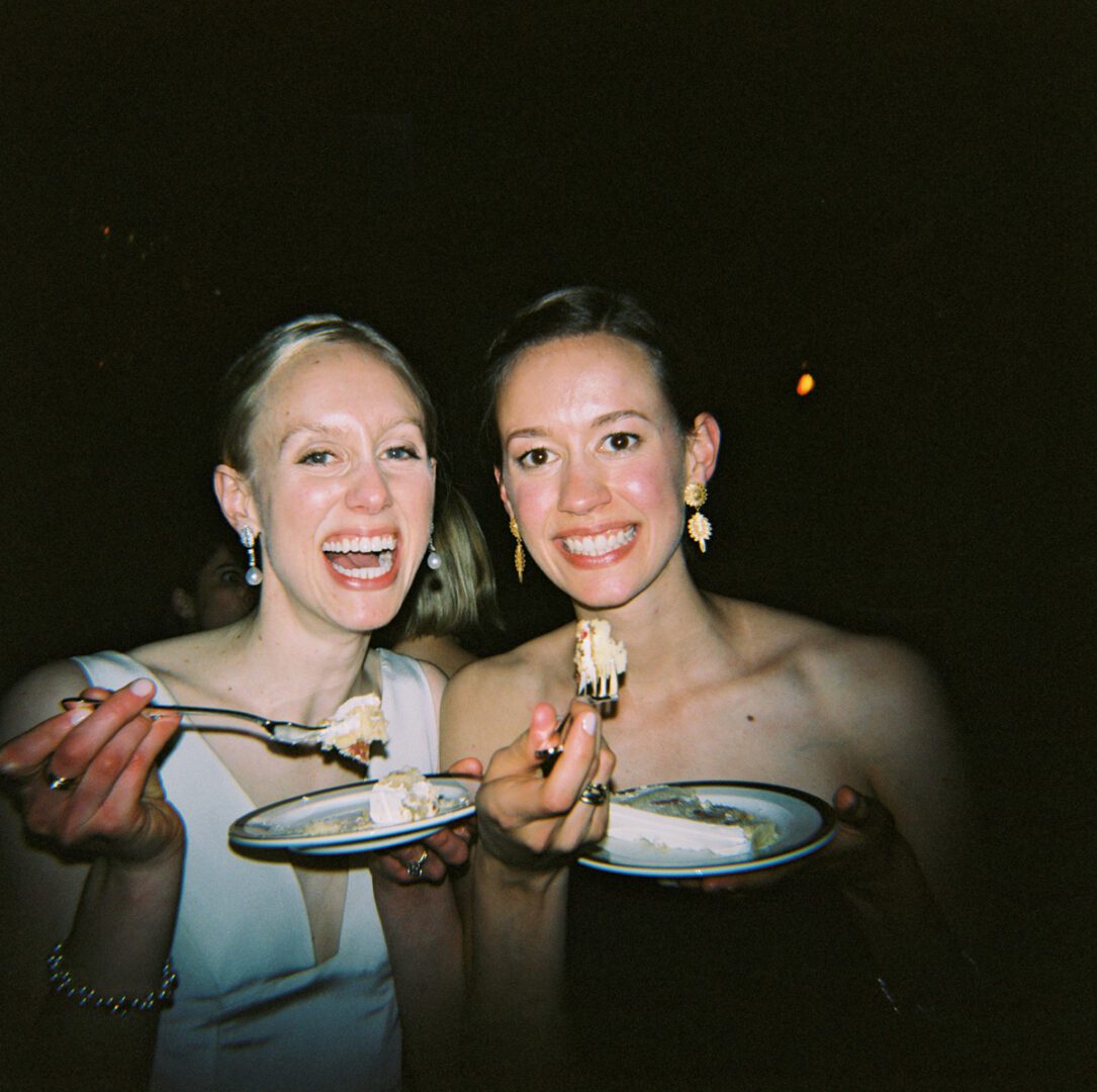 Two women smiling and eating the cake