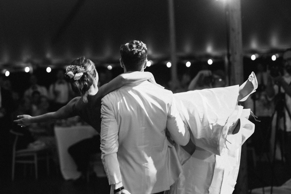 Black and white image of the groom picking up the bride