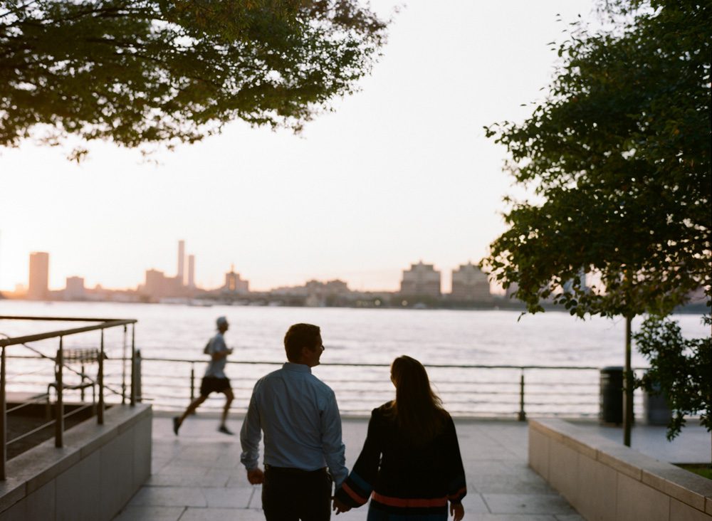 A boy and a girl holding each other hand near a lake