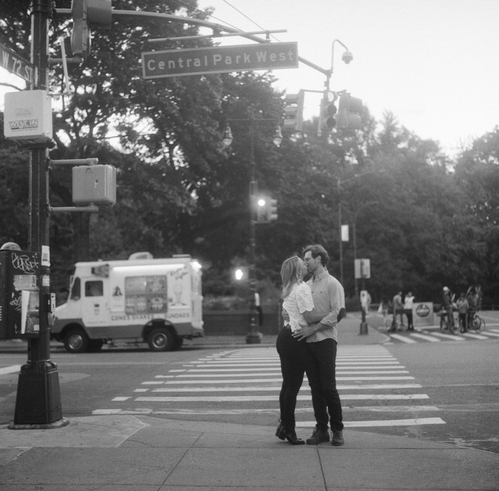 Black and white image of a couple kissing on the road