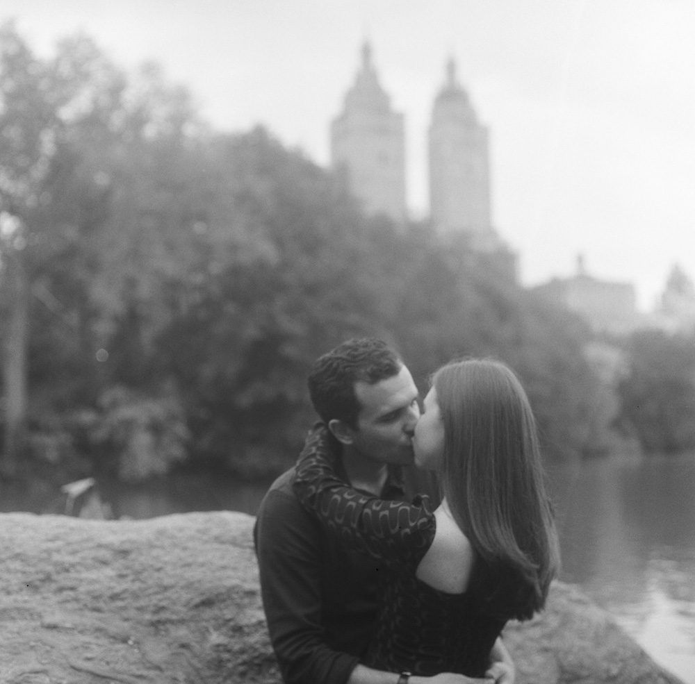a couple kissing near a rock and a lake